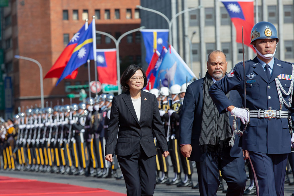 The President escorts a visiting leader of state past a tri-service honor guard.