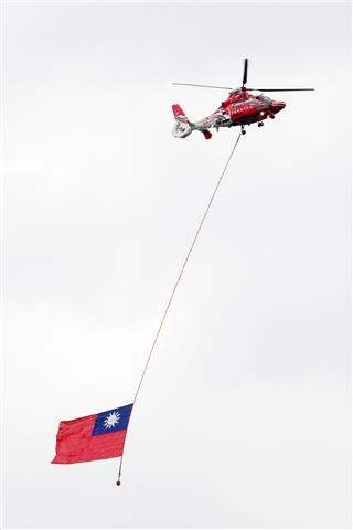 空勤總隊的直升機，吊掛巨幅的國旗，飛過總統府上空。（5-3）