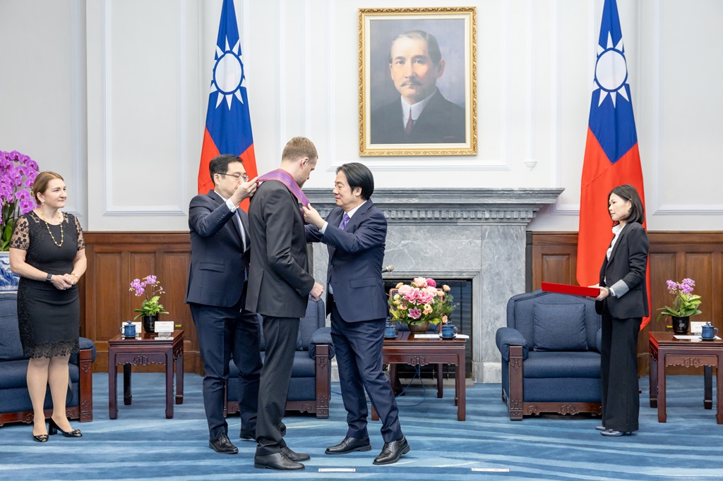 總統為受勳人佩掛勳章,大禮官從旁襄助。