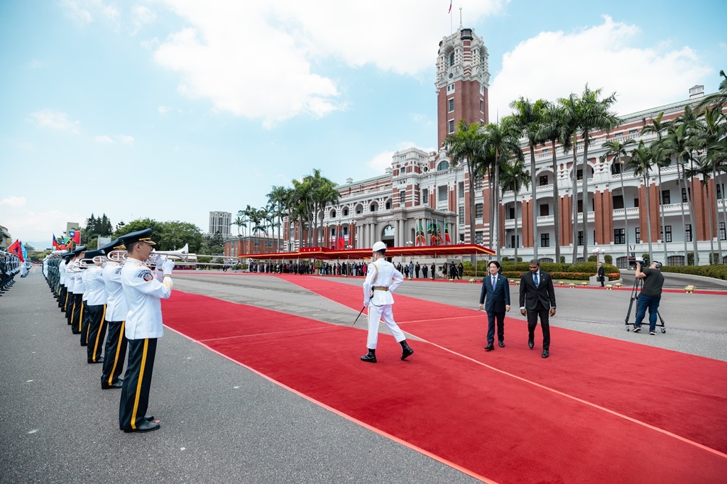 The President escorts a visiting leader of state past a tri-service honor guard.